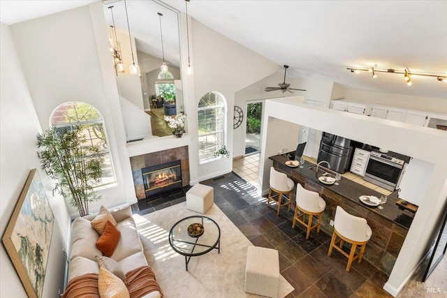 living area with plenty of natural light, a fireplace, ceiling fan, and high vaulted ceiling
