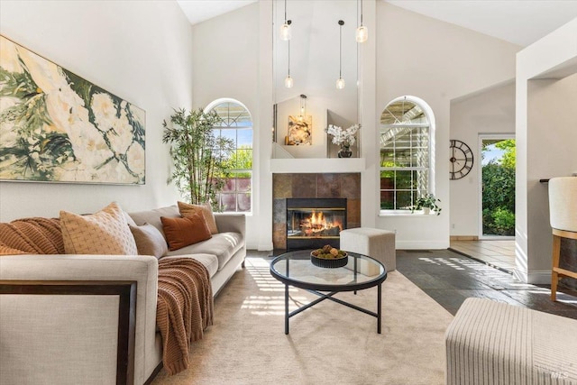 living room featuring baseboards, a tiled fireplace, and high vaulted ceiling