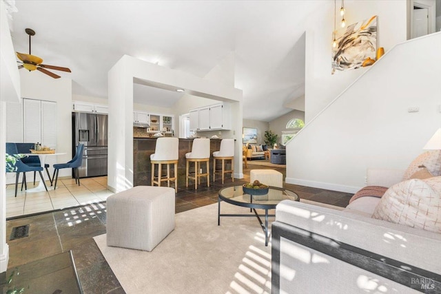 living area with visible vents, a ceiling fan, baseboards, and high vaulted ceiling