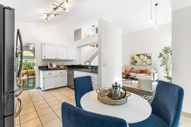 kitchen with white cabinets, stainless steel appliances, dark countertops, a sink, and open floor plan