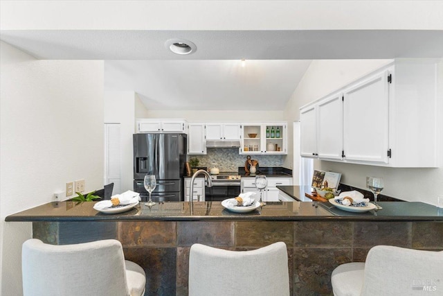 kitchen featuring a peninsula, dark countertops, appliances with stainless steel finishes, and under cabinet range hood