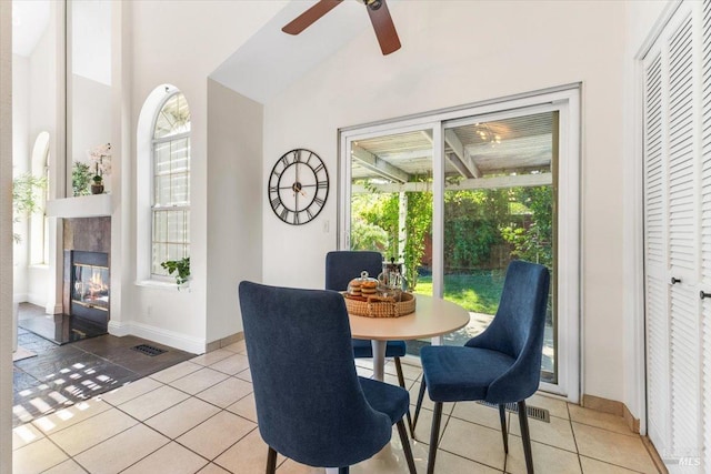 dining room with vaulted ceiling, light tile patterned flooring, baseboards, a tiled fireplace, and ceiling fan
