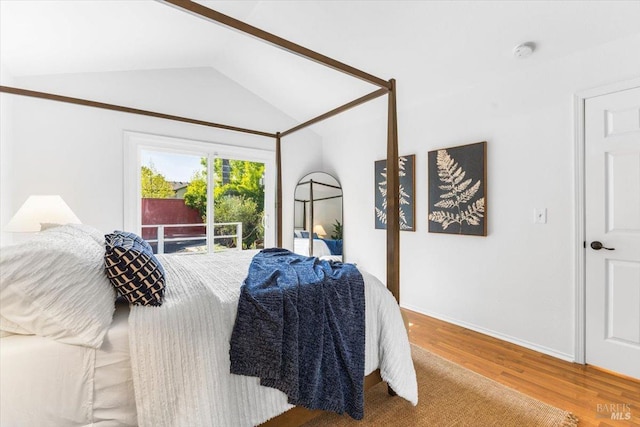 bedroom with wood finished floors, lofted ceiling, and baseboards