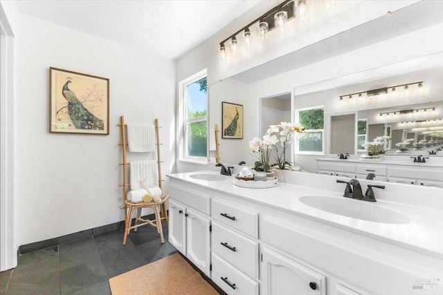 full bath with double vanity, baseboards, and a sink