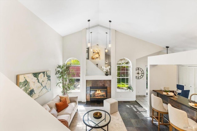 living room with a tile fireplace, baseboards, and high vaulted ceiling