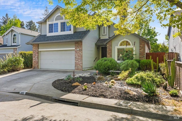 traditional-style home with fence, a shingled roof, driveway, brick siding, and a garage