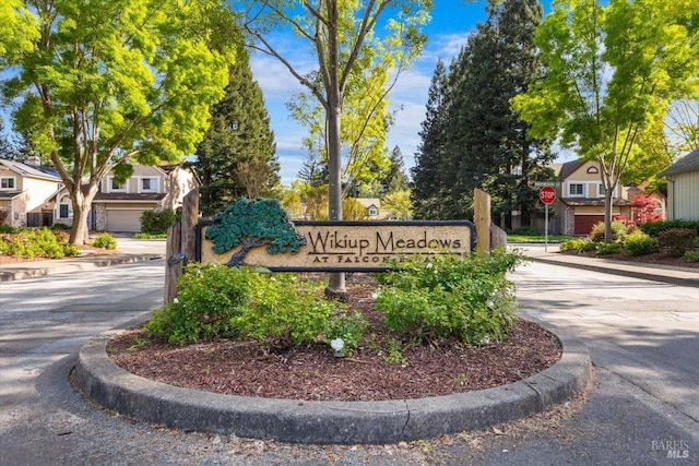 community sign with driveway and a residential view