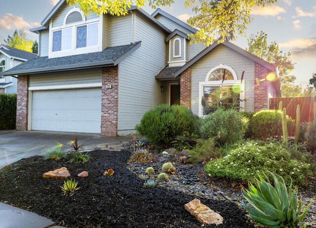 view of front of house featuring brick siding, driveway, a garage, and fence