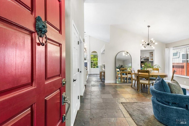 entrance foyer with plenty of natural light, an inviting chandelier, stone tile flooring, and baseboards