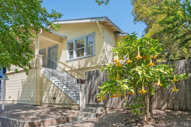 view of side of home featuring stairway and fence