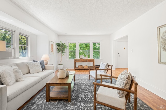 living area featuring light wood-style floors, a textured ceiling, and baseboards