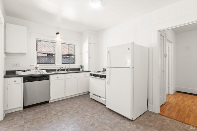kitchen with white cabinetry, dark countertops, a sink, and white appliances