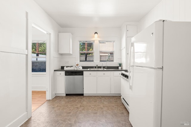 kitchen with white cabinets, dark countertops, white appliances, and a sink