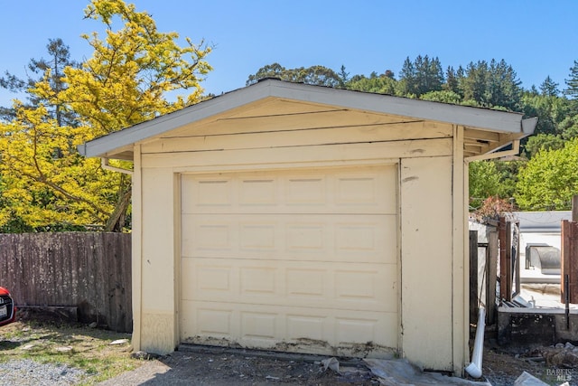 detached garage featuring fence and driveway