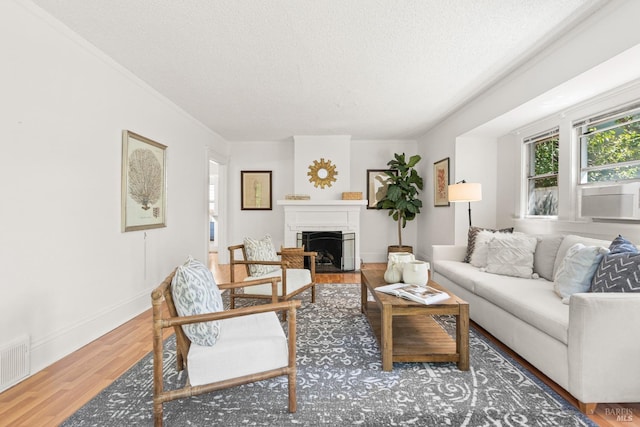 living room with a textured ceiling, baseboards, visible vents, wood finished floors, and a fireplace