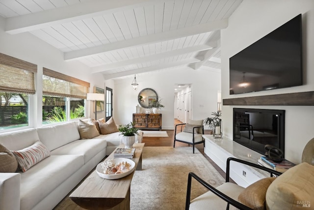 living room with a glass covered fireplace, wood finished floors, vaulted ceiling with beams, and wooden ceiling