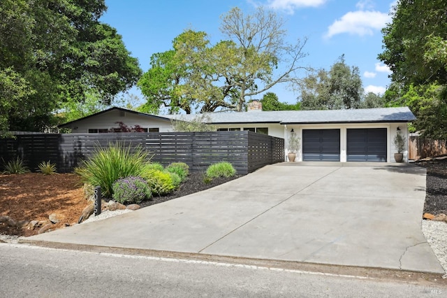 view of front of property featuring a chimney, driveway, fence, a garage, and stucco siding