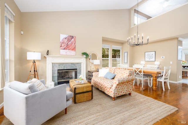 living room with baseboards, a chandelier, a premium fireplace, wood finished floors, and high vaulted ceiling