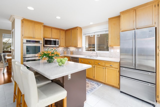 kitchen with recessed lighting, stainless steel appliances, a sink, a kitchen island, and tasteful backsplash