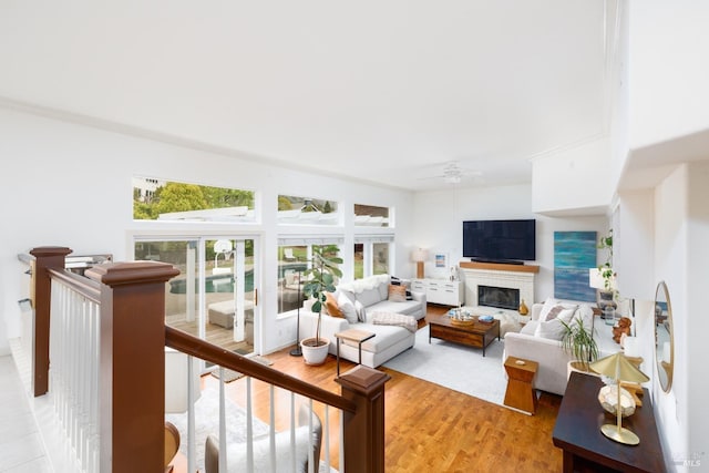 living area with light wood-style flooring, a fireplace, and ceiling fan