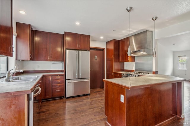 kitchen with stainless steel appliances, dark wood finished floors, a sink, and wall chimney exhaust hood