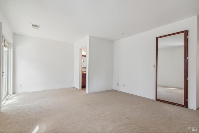 unfurnished bedroom featuring visible vents, light carpet, and ensuite bathroom