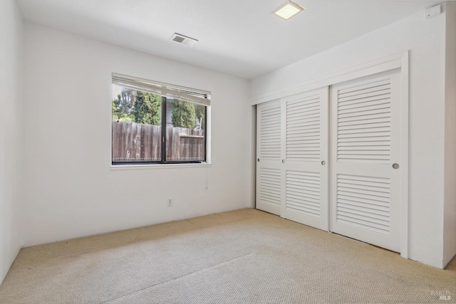 unfurnished bedroom featuring carpet floors, visible vents, and a closet