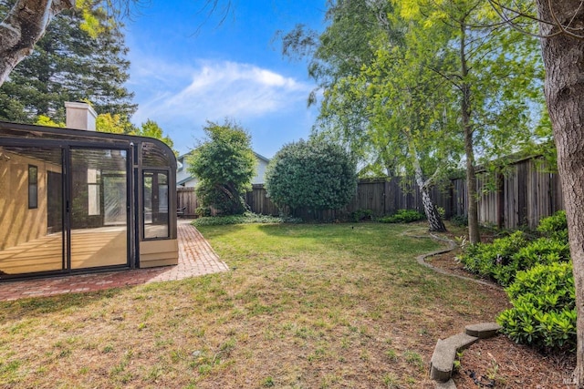 view of yard featuring a sunroom and a fenced backyard