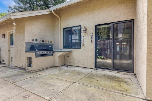 entrance to property with a patio, stucco siding, and exterior kitchen
