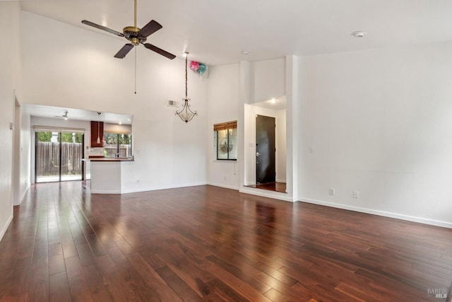 unfurnished living room featuring visible vents, baseboards, ceiling fan, dark wood-style floors, and high vaulted ceiling