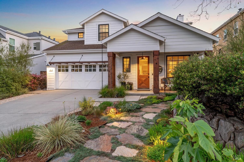 craftsman-style home with a garage, driveway, and a porch