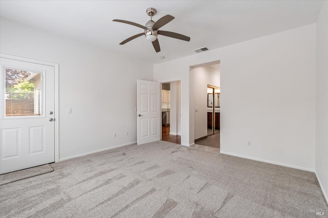 unfurnished bedroom featuring a ceiling fan, carpet floors, baseboards, ensuite bath, and visible vents