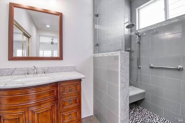full bath featuring a ceiling fan, vanity, and a walk in shower