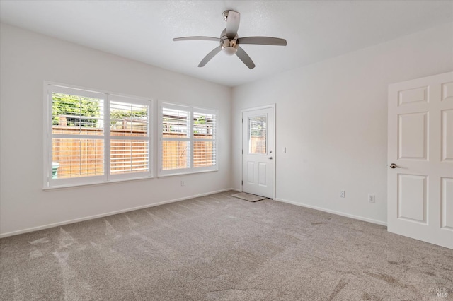 carpeted spare room with a ceiling fan, baseboards, and a wealth of natural light