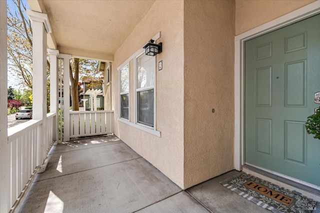 view of exterior entry featuring stucco siding and a porch