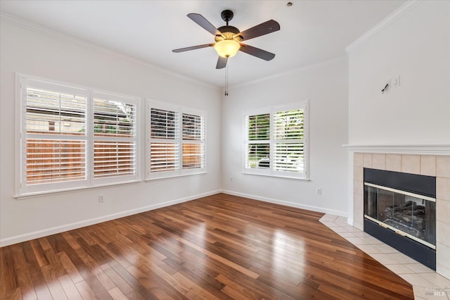 unfurnished living room with light wood-style floors, ceiling fan, a tile fireplace, baseboards, and ornamental molding