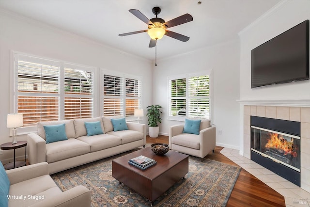living area featuring a fireplace, wood finished floors, crown molding, and a ceiling fan