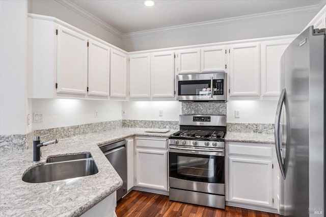 kitchen with white cabinets, a sink, dark wood-style flooring, appliances with stainless steel finishes, and ornamental molding