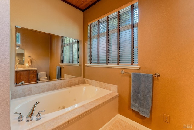 bathroom featuring baseboards, a jetted tub, vanity, and toilet