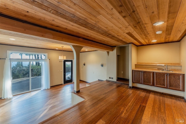 unfurnished living room with wood ceiling, hardwood / wood-style flooring, baseboards, and a sink