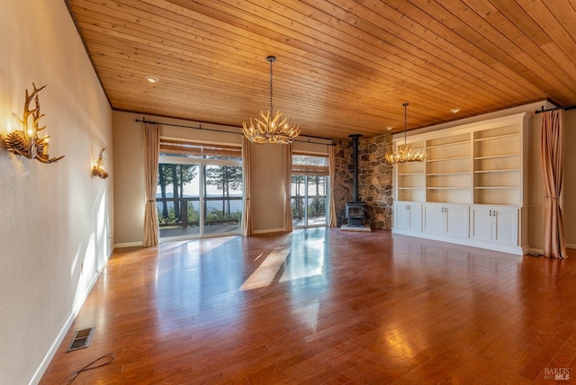 unfurnished living room with wood ceiling, a notable chandelier, a wood stove, and visible vents