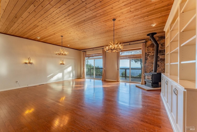interior space with wood ceiling, wood finished floors, an inviting chandelier, and a wood stove