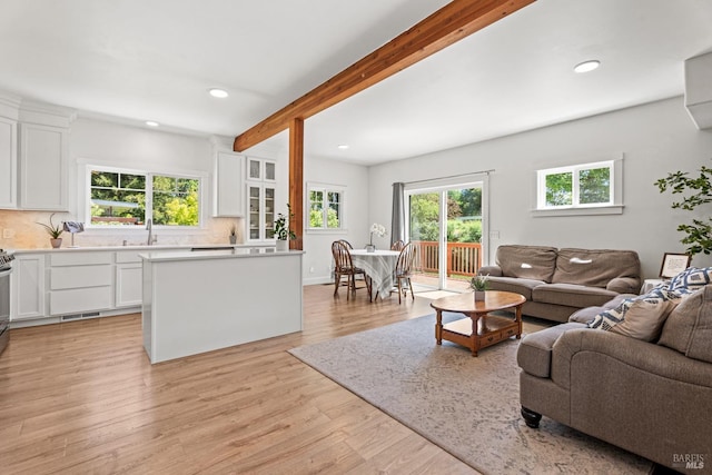 living area featuring recessed lighting, beamed ceiling, visible vents, and light wood-style flooring