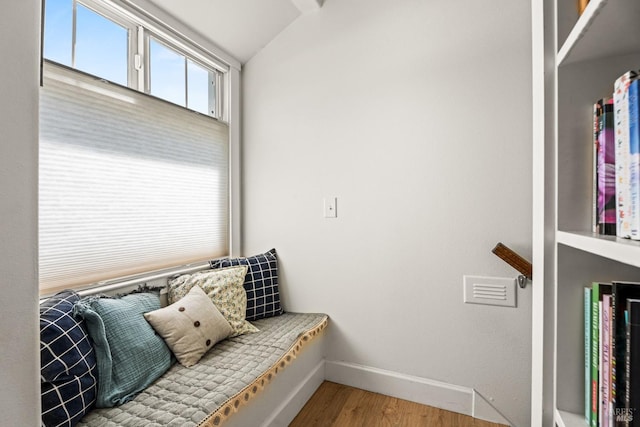 interior space with baseboards, wood finished floors, and lofted ceiling