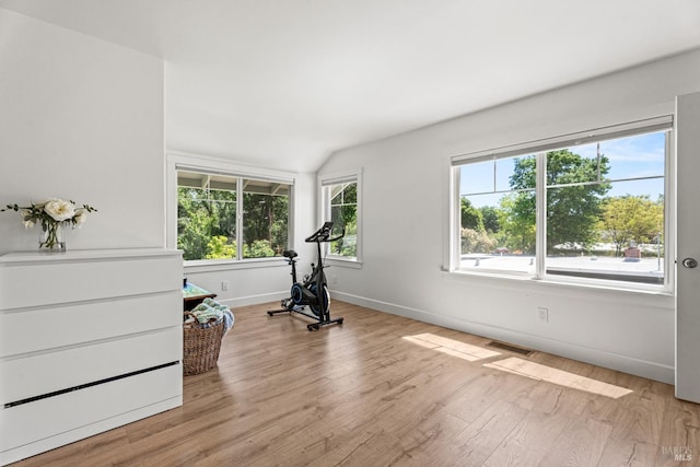 exercise area with visible vents, baseboards, light wood finished floors, and lofted ceiling