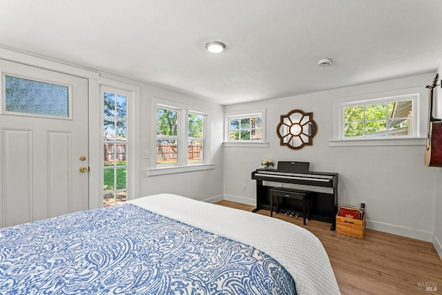 bedroom featuring baseboards, wood finished floors, and access to outside