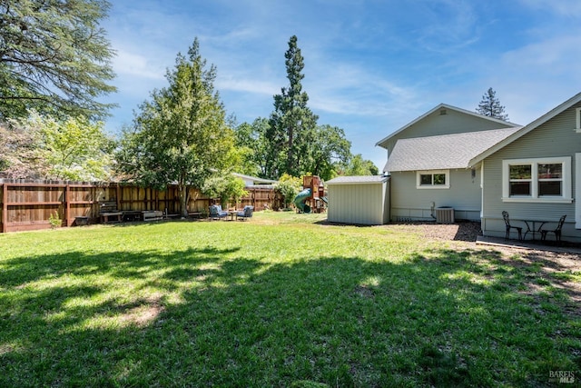 view of yard with central air condition unit, a fenced backyard, and a playground