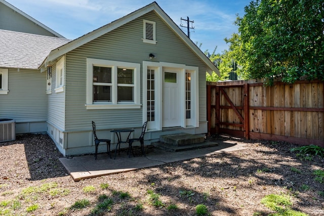 rear view of house featuring fence, roof with shingles, entry steps, central air condition unit, and a patio