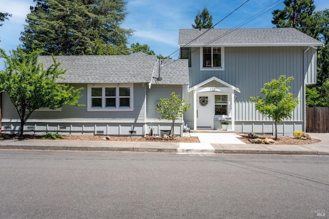 traditional home featuring a shingled roof and fence