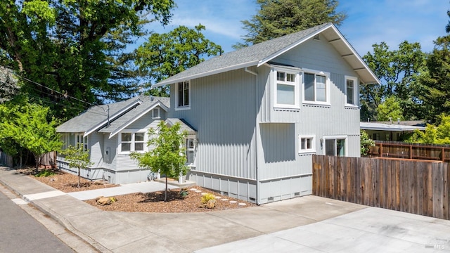view of side of property with fence and a shingled roof